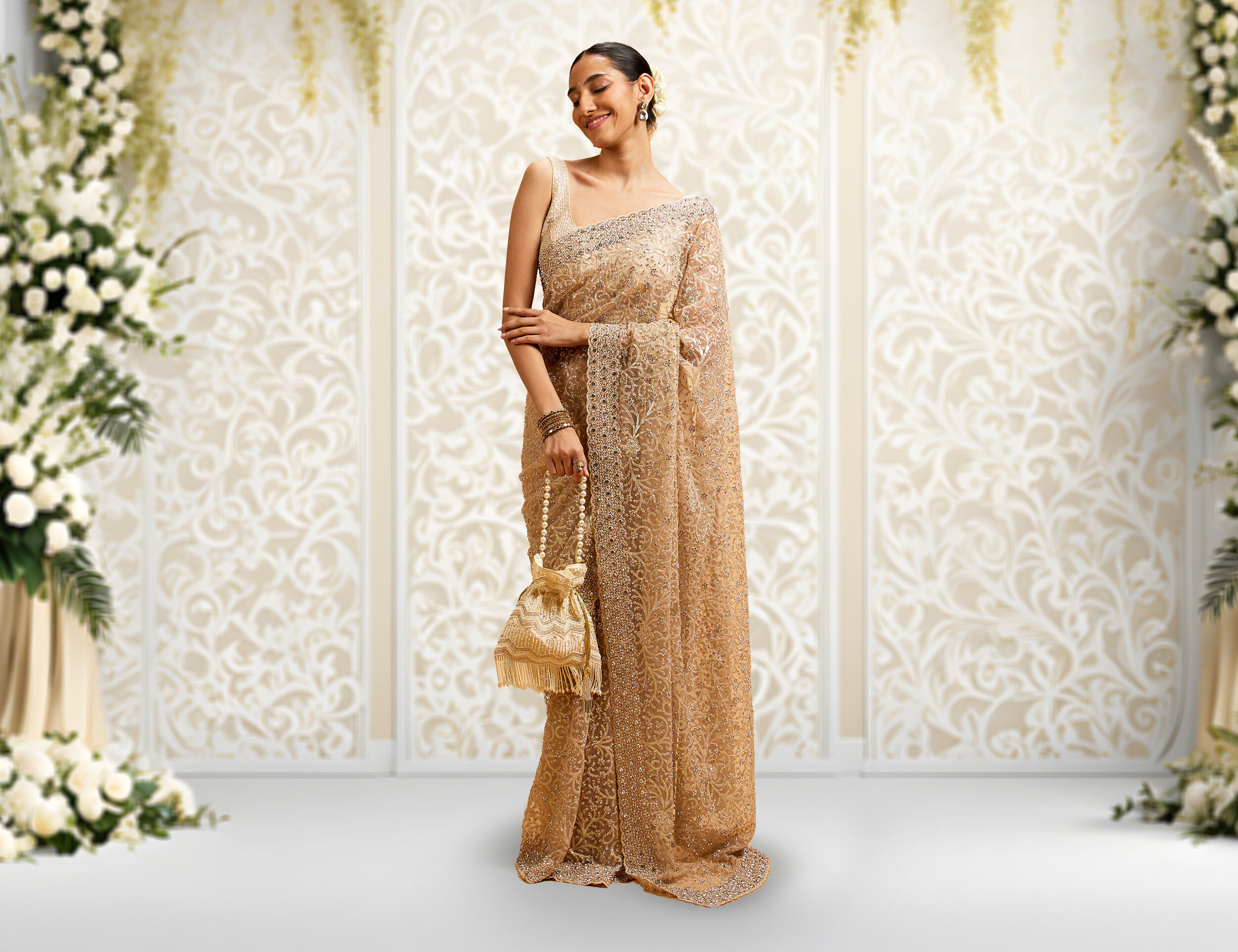 Woman wearing a elegant golden beige saree with golden colour potli bag in hand
